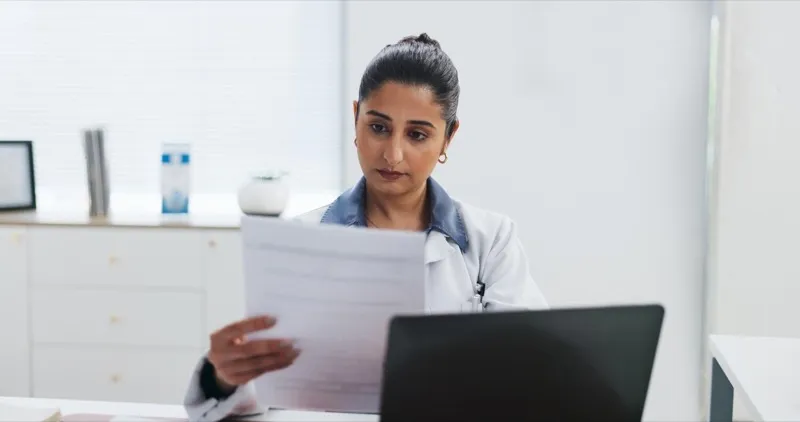 Healthcare administrator reviewing documents and planning at a hospital desk